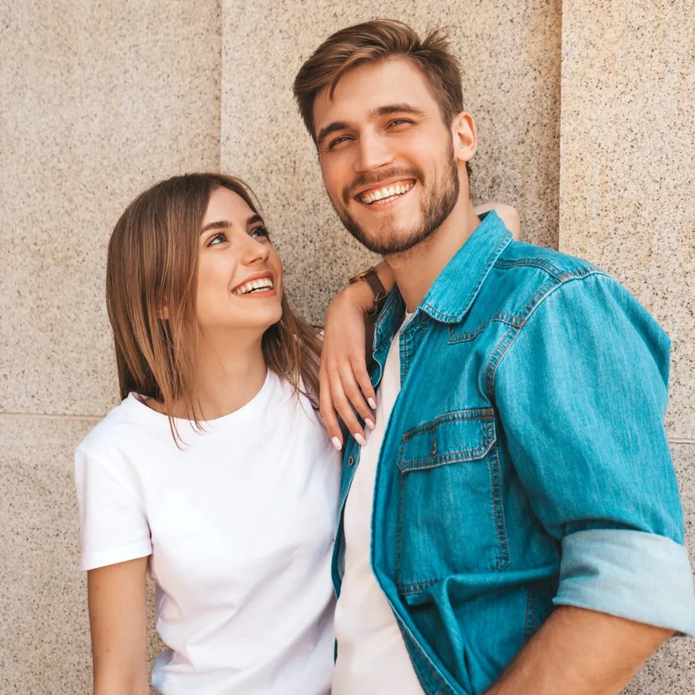 Portrait of smiling beautiful girl and her handsome boyfriend. Woman in casual summer jeans clothes. Happy cheerful family. Female having fun on the street background